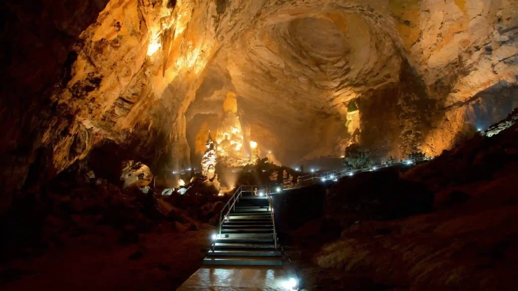 Escaleras iluminadas en el interior de Grutas de Cacahuamilpa, rodeadas de impresionantes formaciones rocosas y estalactitas bajo cálida luz artificial.