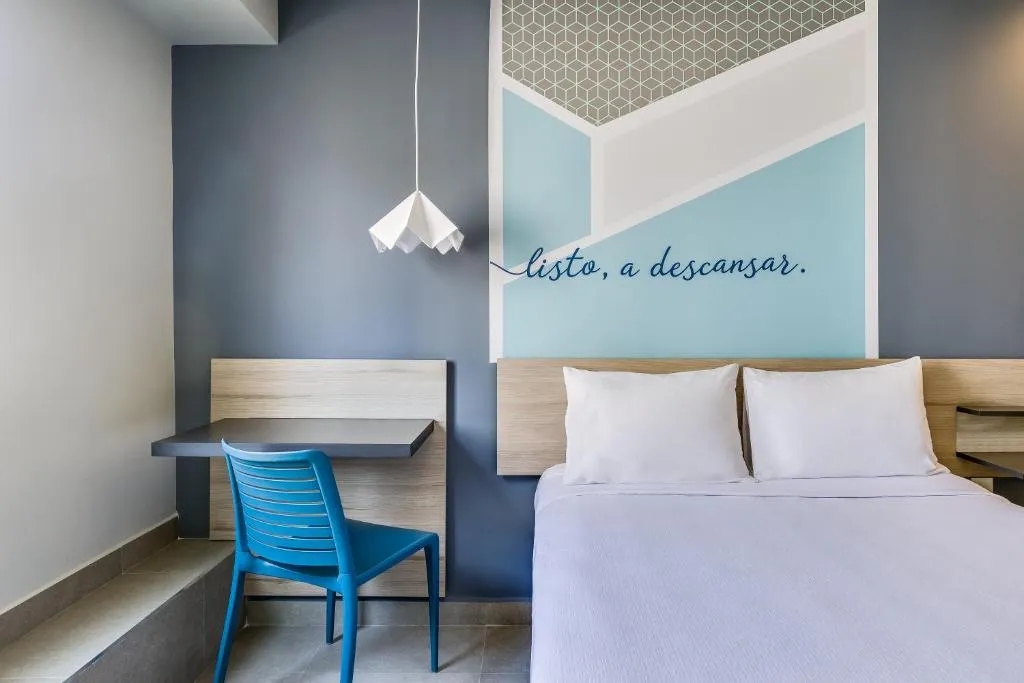 Habitación individual moderna con cama matrimonial, escritorio y decoración minimalista en hotel cómodo y accesible.